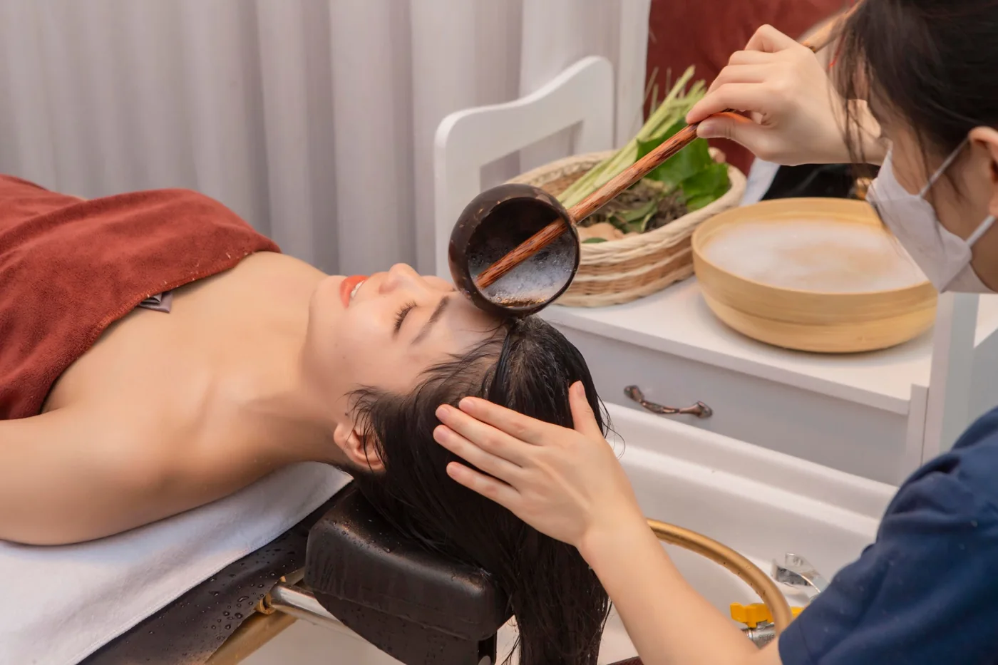 Kỹ thuật viên gội đầu bằng nước thảo mộc